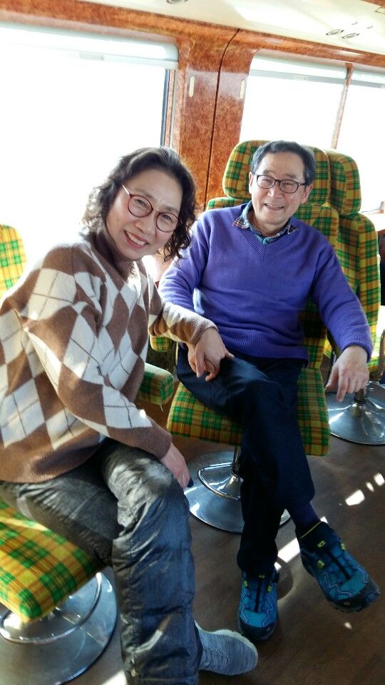 기차 좌석에 나란히 앉아 웃는 두 사람