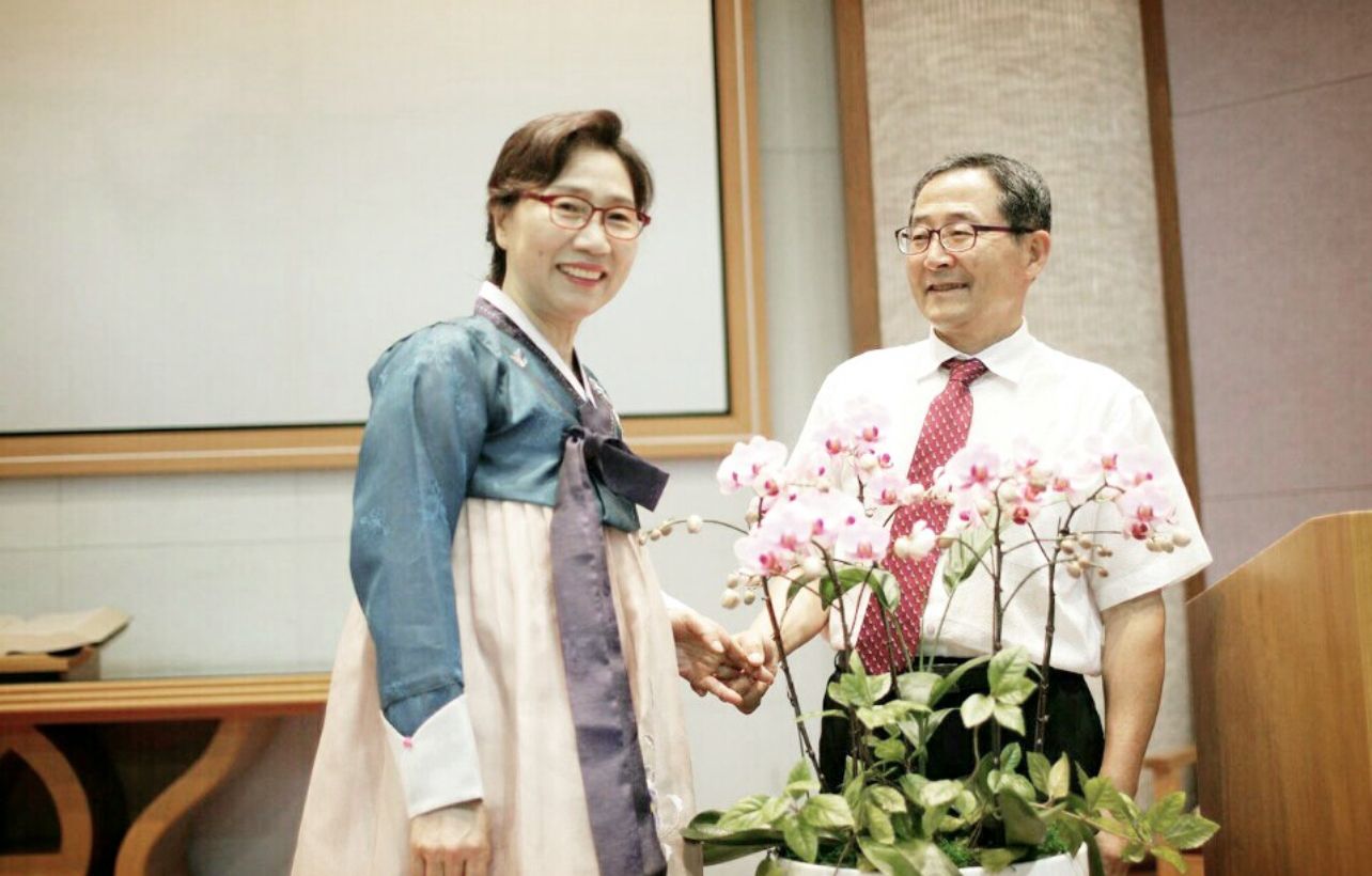 한복 차림의 장정숙 님과 손을 맞잡은 남편, 앞에 놓인 호접란