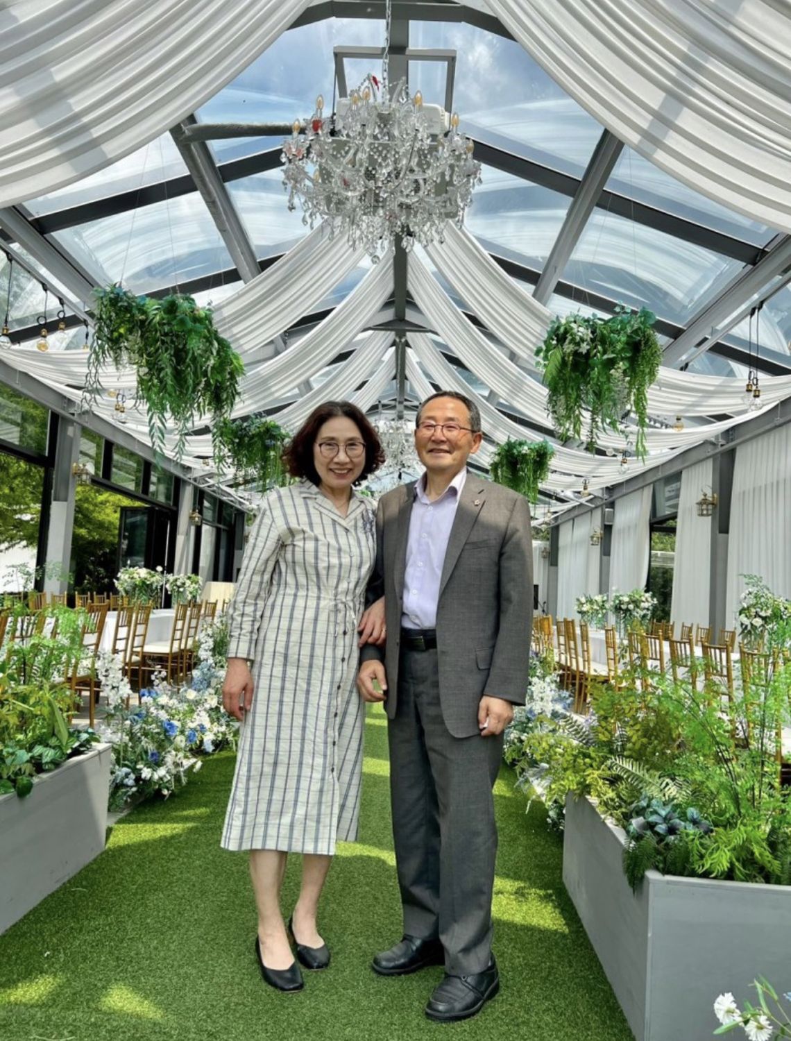 꽃과 초록으로 꾸민 유리온실 예식장에 함께 선 두 사람