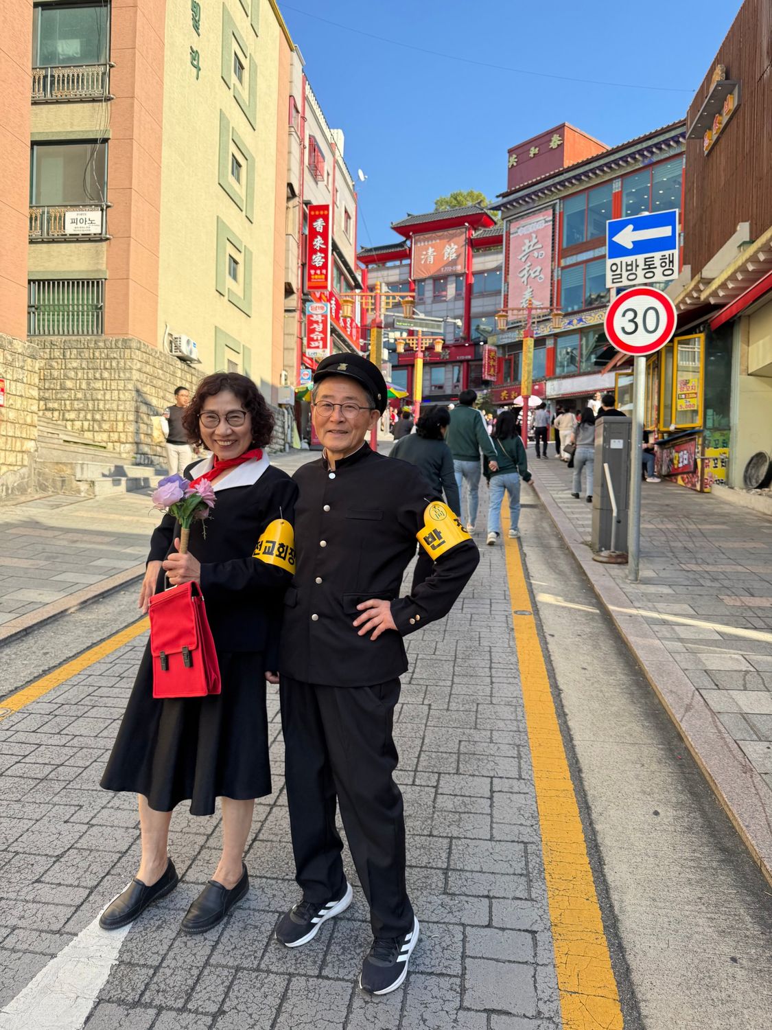옛 교복을 입고 거리에서 장난스럽게 포즈를 취한 두 사람